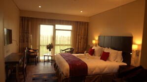 Habitación de hotel con una cama grande, un escritorio, una silla y vistas al exterior.
