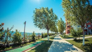 Une journée ensoleillée dans un quartier résidentiel, avec un sentier, des espaces verts et une piscine.