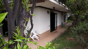 A white building with a tiled porch, a black door, and a white plastic chair. - Apartment "B" in cottage with garden, parking and Wi-Fi (Ercolano)