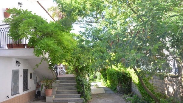 A staircase leading up to a white building with a balcony, surrounded by lush greenery and potted plants. - Apartment "B" in cottage with garden, parking and Wi-Fi (Ercolano)