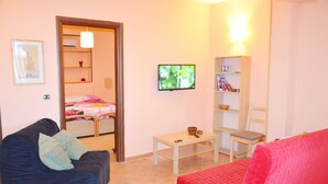 A living room with a black sofa, a red sofa, a small table, a television, and a bookshelf. - Apartment "B" in cottage with garden, parking and Wi-Fi (Ercolano)