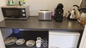 A compact kitchen with a microwave, toaster, kettle, and a coffee maker. There are plates, a mug, and a bottle of dish soap on the counter. - The Wee Studio For Two (Stirling)