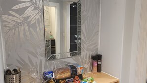 A bathroom with a mirror, a shelf with various toiletries, and a decorative wall pattern. - The Wee Studio For Two (Stirling)