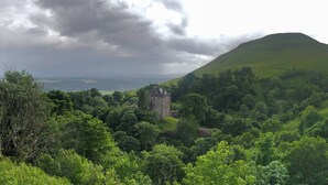 A castle surrounded by lush green hills and dense forest. - The Wee Studio For Two (Stirling)