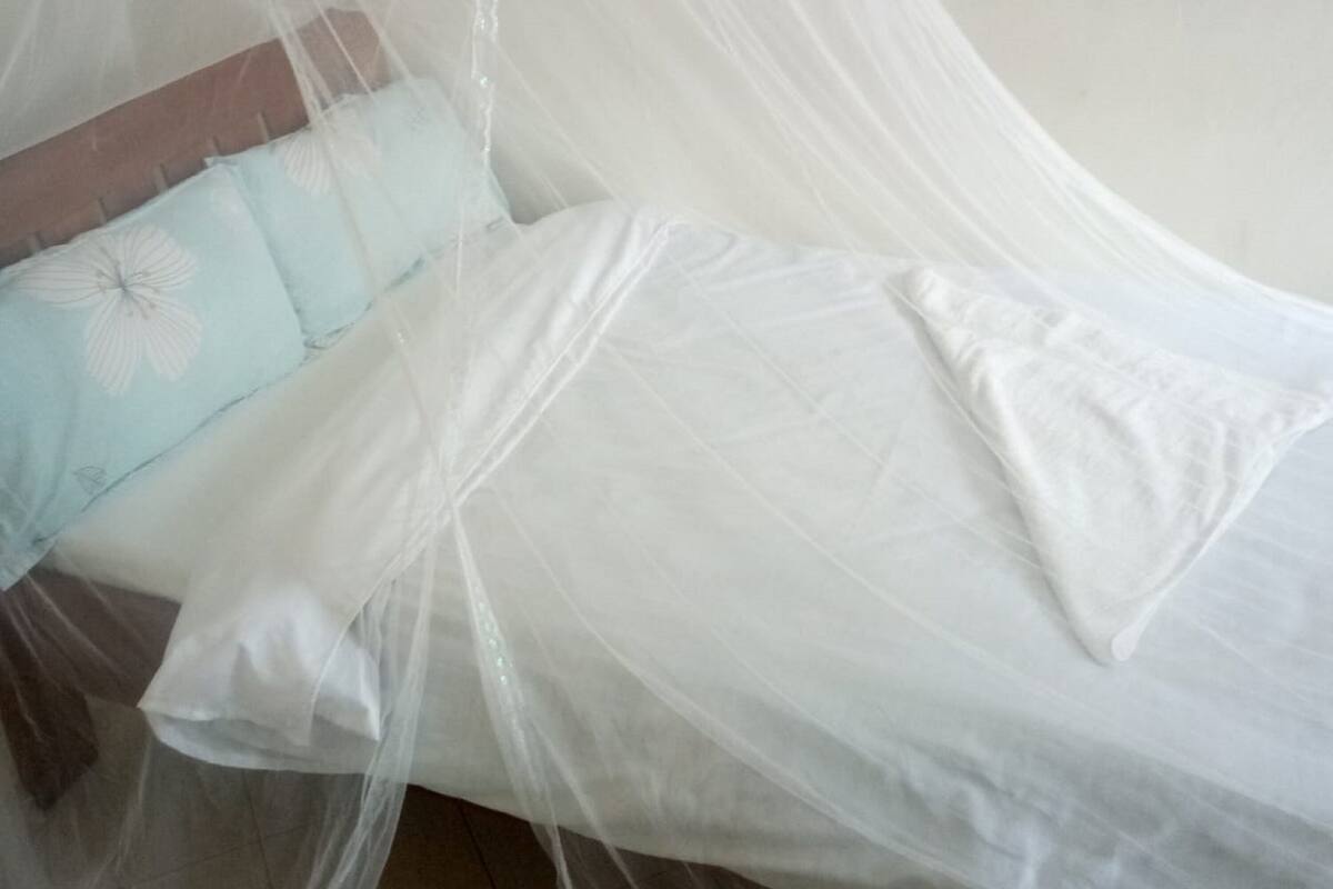 Cama com lençol branco e travesseiro azul claro estampado com flores.