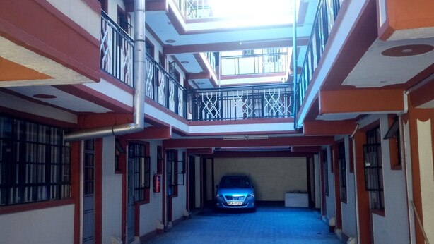 A multi-level building with a central open space and a car parked in the middle. - Sunvasha Hotel (Naivasha)