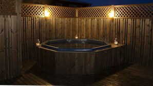 Una bañera de madera con dos faroles en un balcón, rodeada por una valla de madera.