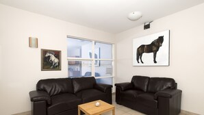 Una sala de estar moderna con dos sofás de cuero negro, una mesa de centro de madera y un ventanal grande.