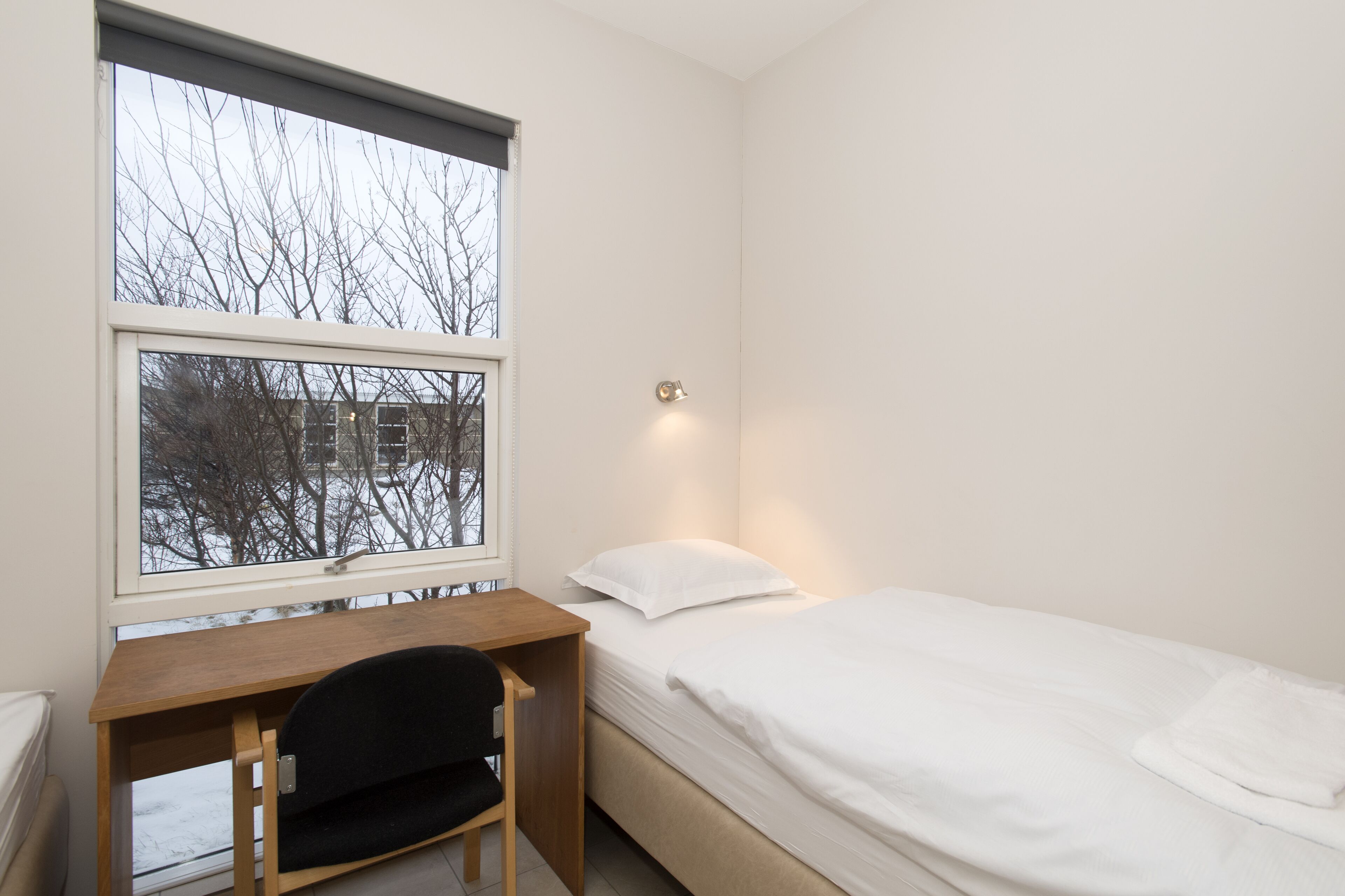 Une chambre avec un lit simple, un bureau et une chaise.