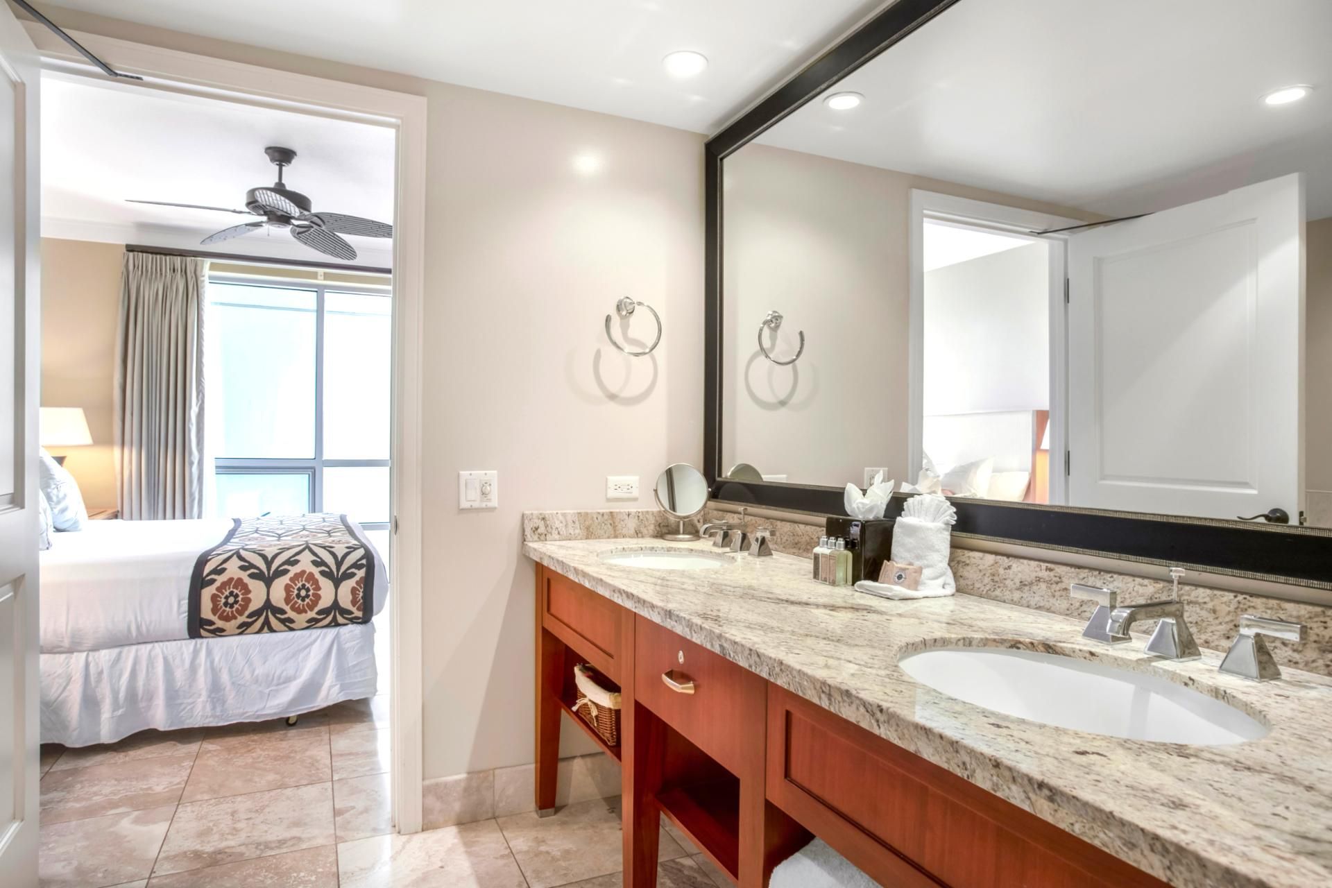 Une salle de bain d’hôtel avec deux lavabos, un grand miroir et un ventilateur de plafond.