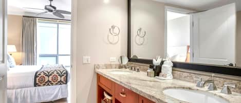 Une salle de bain d’hôtel avec deux lavabos, un grand miroir et un ventilateur de plafond.