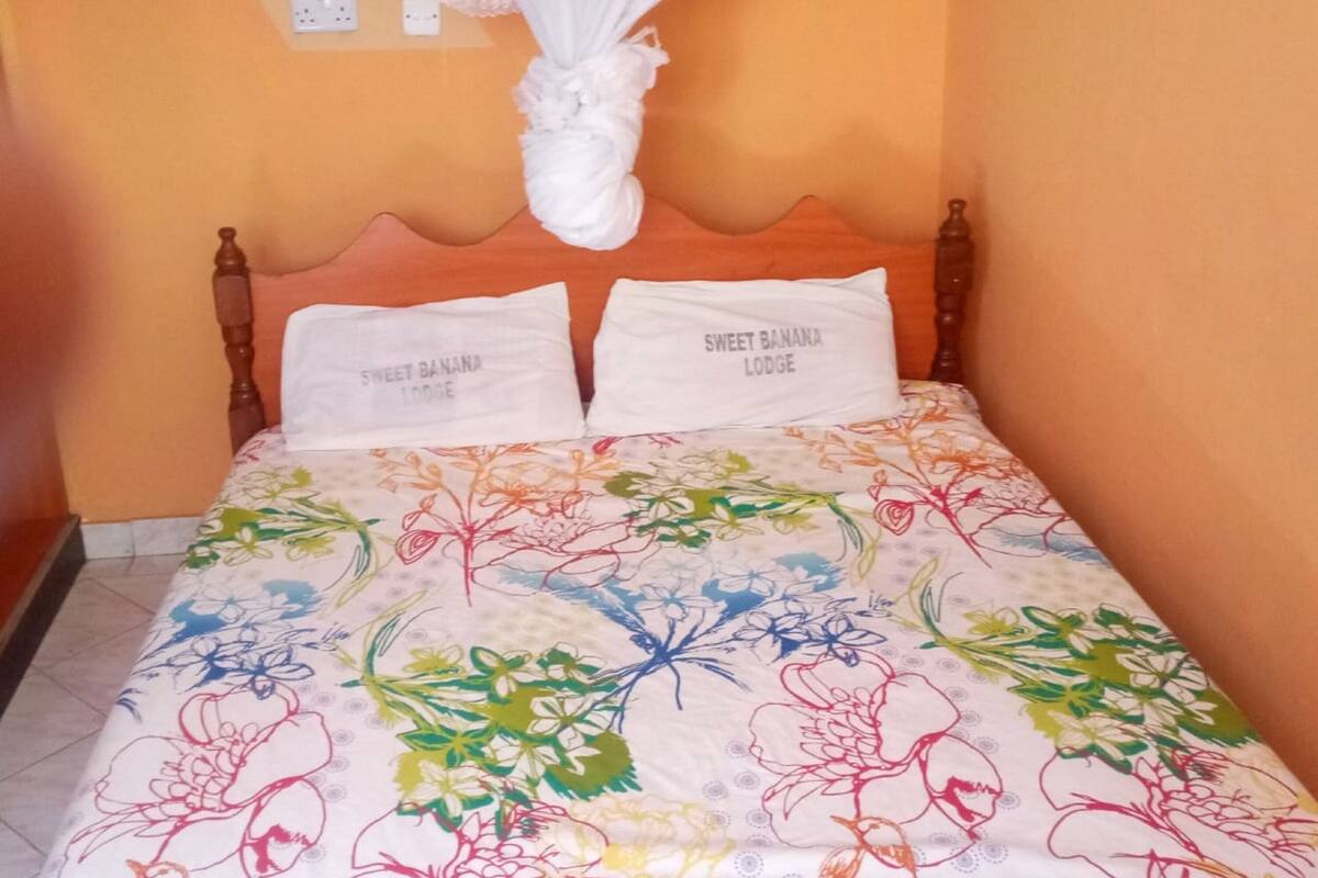 A bed with a floral bedspread, two pillows with text, and a mosquito net above.
