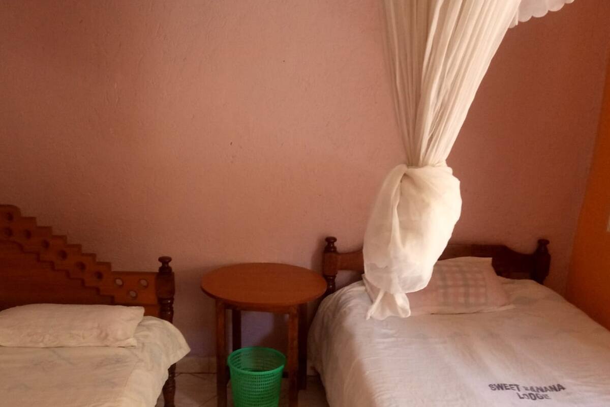 A room with two beds, a small round table, and a green basket.