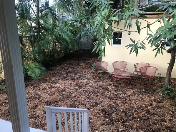 A patio area with a table and chairs, surrounded by dense foliage and a yellow wall. - I. Historic Home Key West style in Coconut Grove Yellow House (Miami)