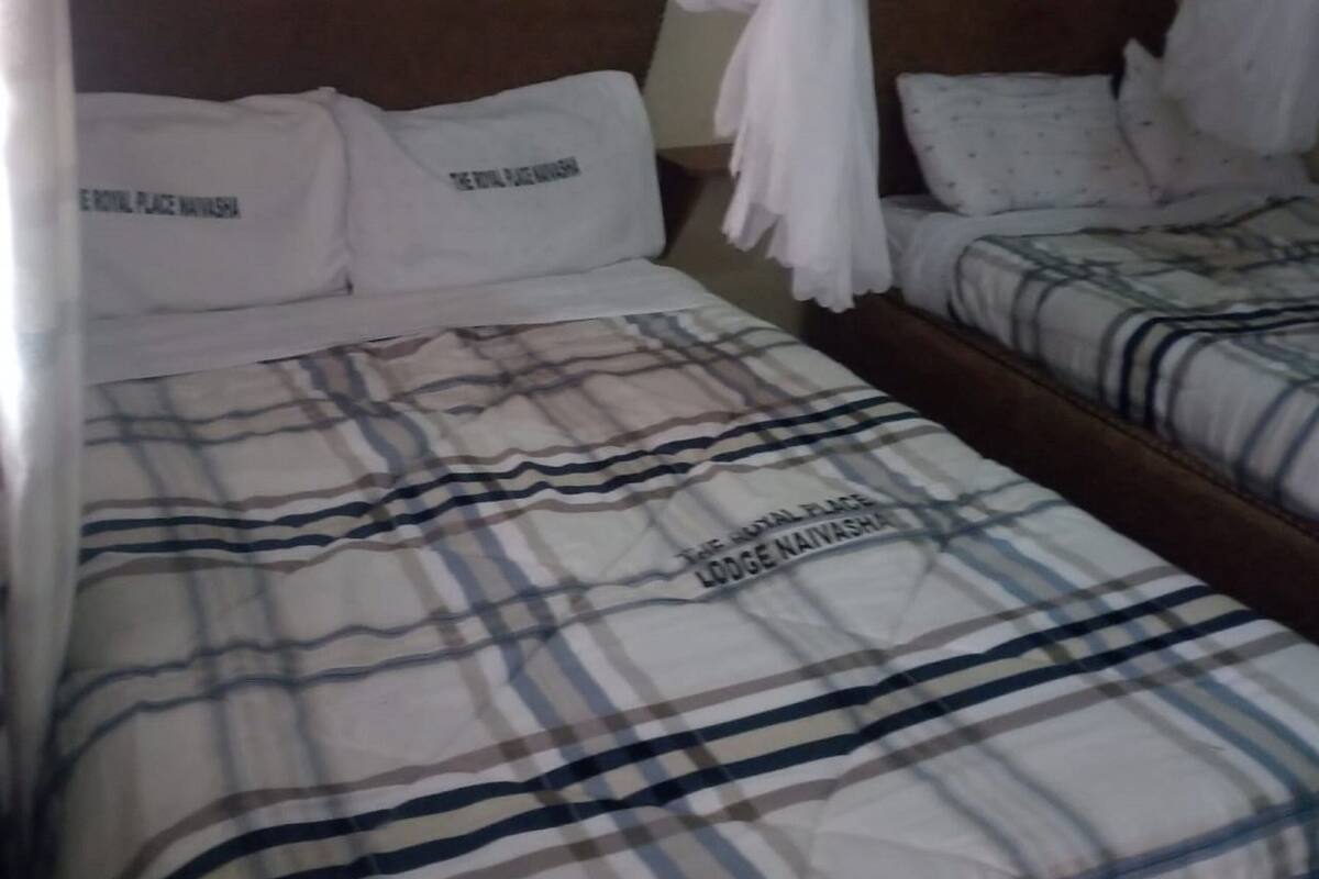 Quarto de hotel com duas camas, cada uma com colcha listrada e almofadas com texto.