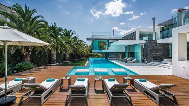Un espace piscine moderne, doté de chaises longues et offrant une vue dégagée sur la piscine.