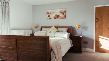 A bedroom with a wooden bed, two bedside lamps, a radiator, and a door.