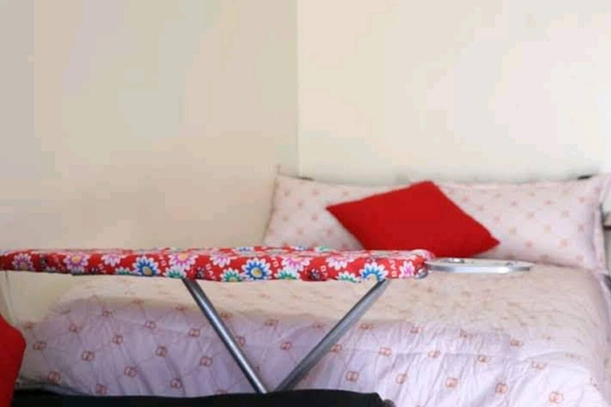 A bed with a floral-patterned bedspread and a red pillow.