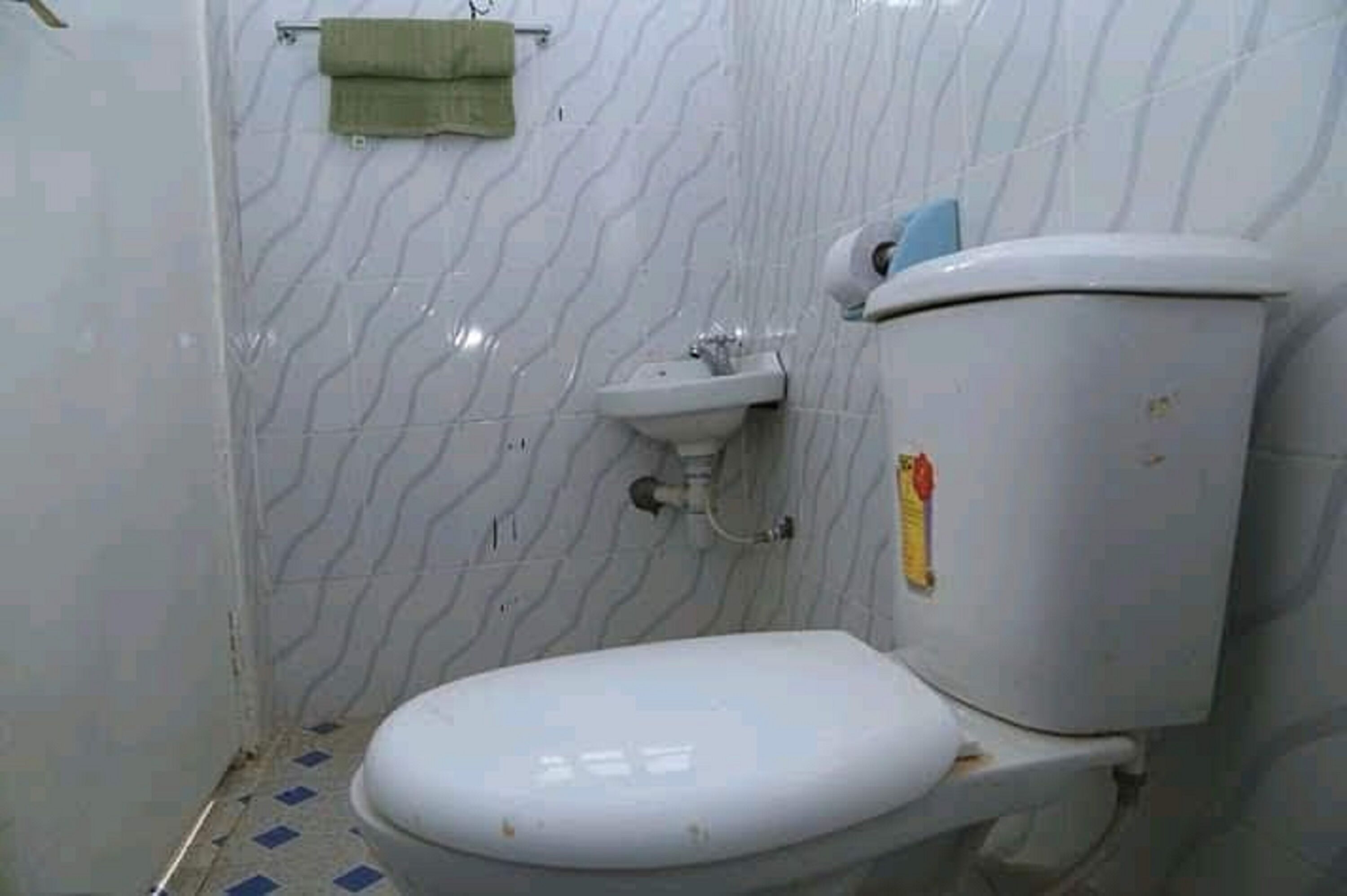 Un baño pequeño y sencillo con inodoro, lavabo y paredes de azulejos.