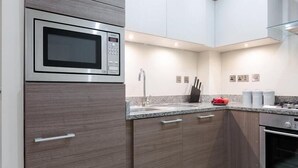 Design appartement | Privékeuken | Een koelkast/vriezer, een magnetron, een oven, een kookplaat