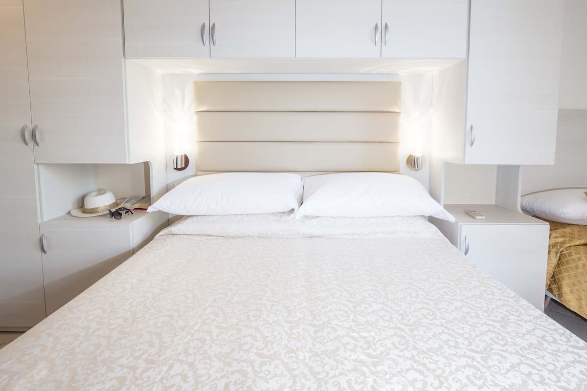 Une chambre bien rangée, avec un grand lit, deux tables de chevet et une armoire.