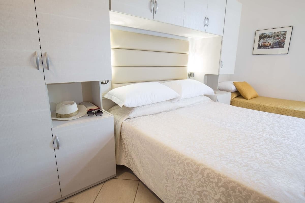 Une chambre à coucher avec un lit, une table de chevet, une armoire et un tableau encadré au mur.