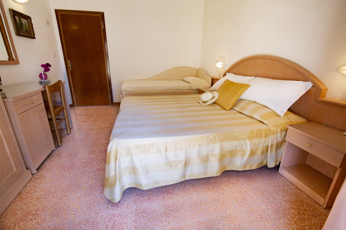 Une chambre à coucher comprenant un lit, une table de chevet, une commode et une armoire en bois.