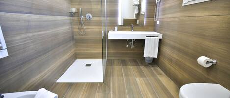 Een moderne badkamer met douche, wastafel, toilet en een douchecabine met glazen wanden.