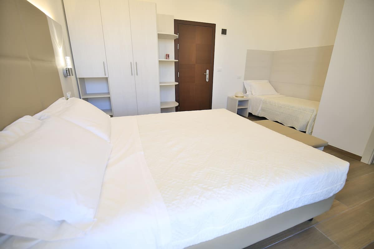 Une chambre à coucher avec un grand lit, une armoire, une table de chevet et un petit bureau.