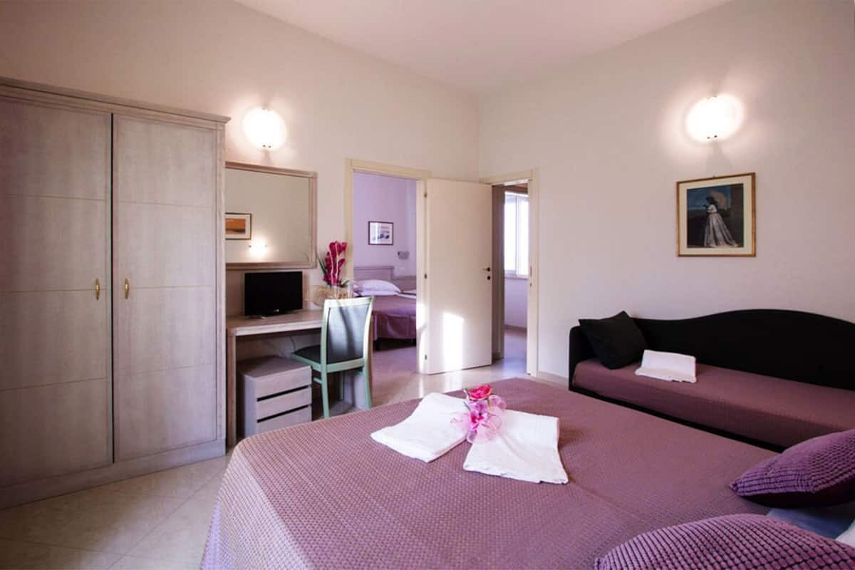 Une chambre à coucher comprenant un lit, un bureau, une chaise, une armoire, un téléviseur et un canapé.