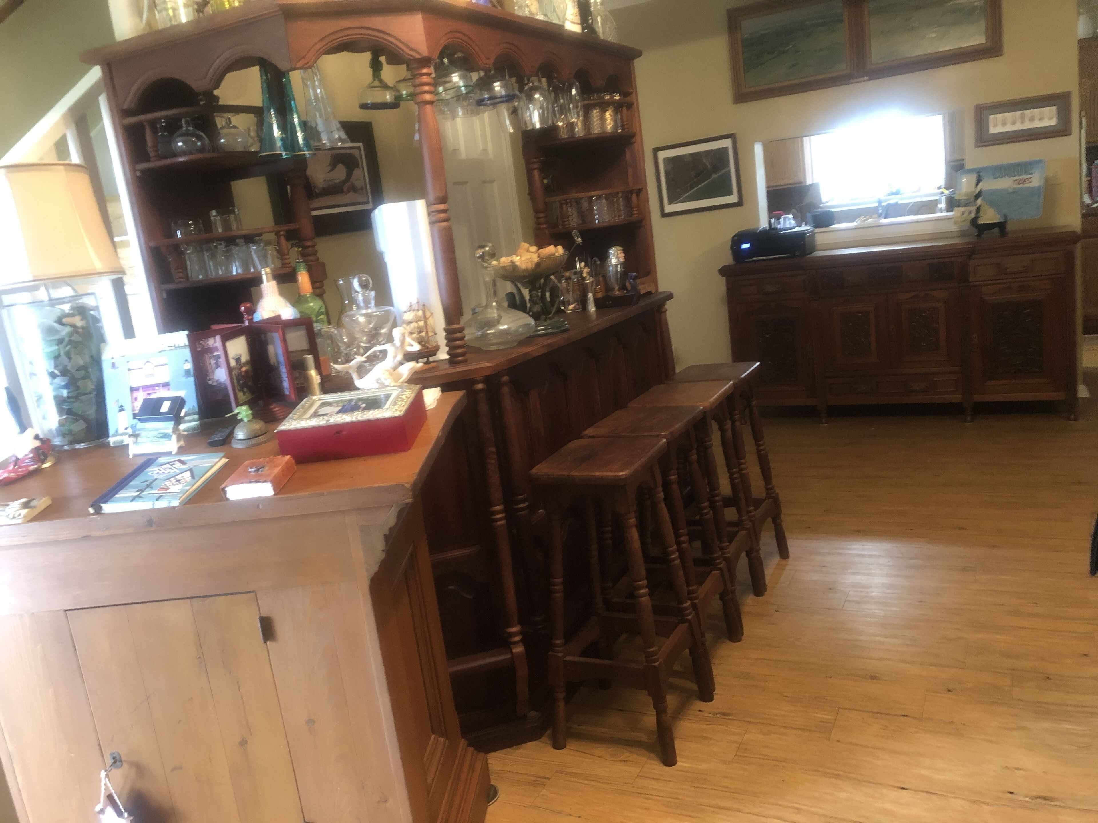 A wooden bar area with stools, shelves with glassware, and a vintage radio.