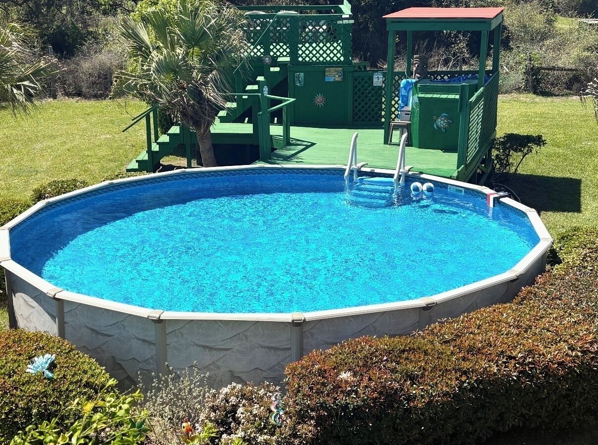 Una piscina al aire libre con un deck verde y una escalera.