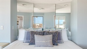 Un dormitorio con una cama grande, un espejo y vista a la playa.