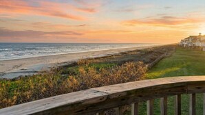 A coastal view with a wooden deck overlooking the beach and ocean. - Beachfront Beauty with Huge Deck & Stunning Views (Galveston)