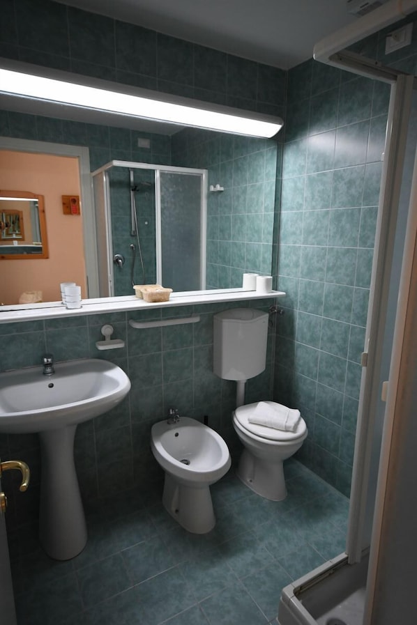 Un baño con lavamanos, bidé, inodoro y cabina de ducha.