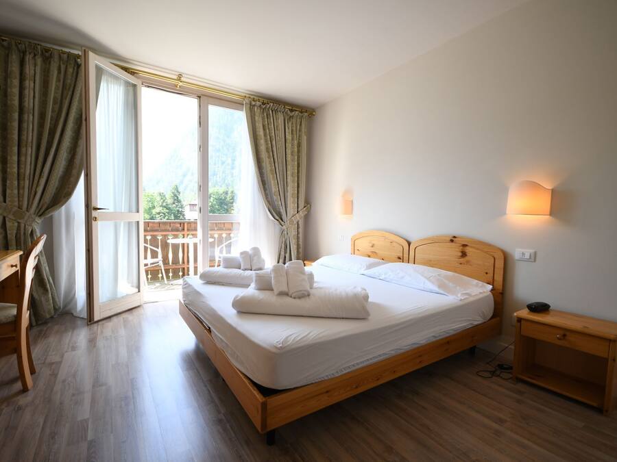 A bedroom with a wooden bed, a desk, and a nightstand.