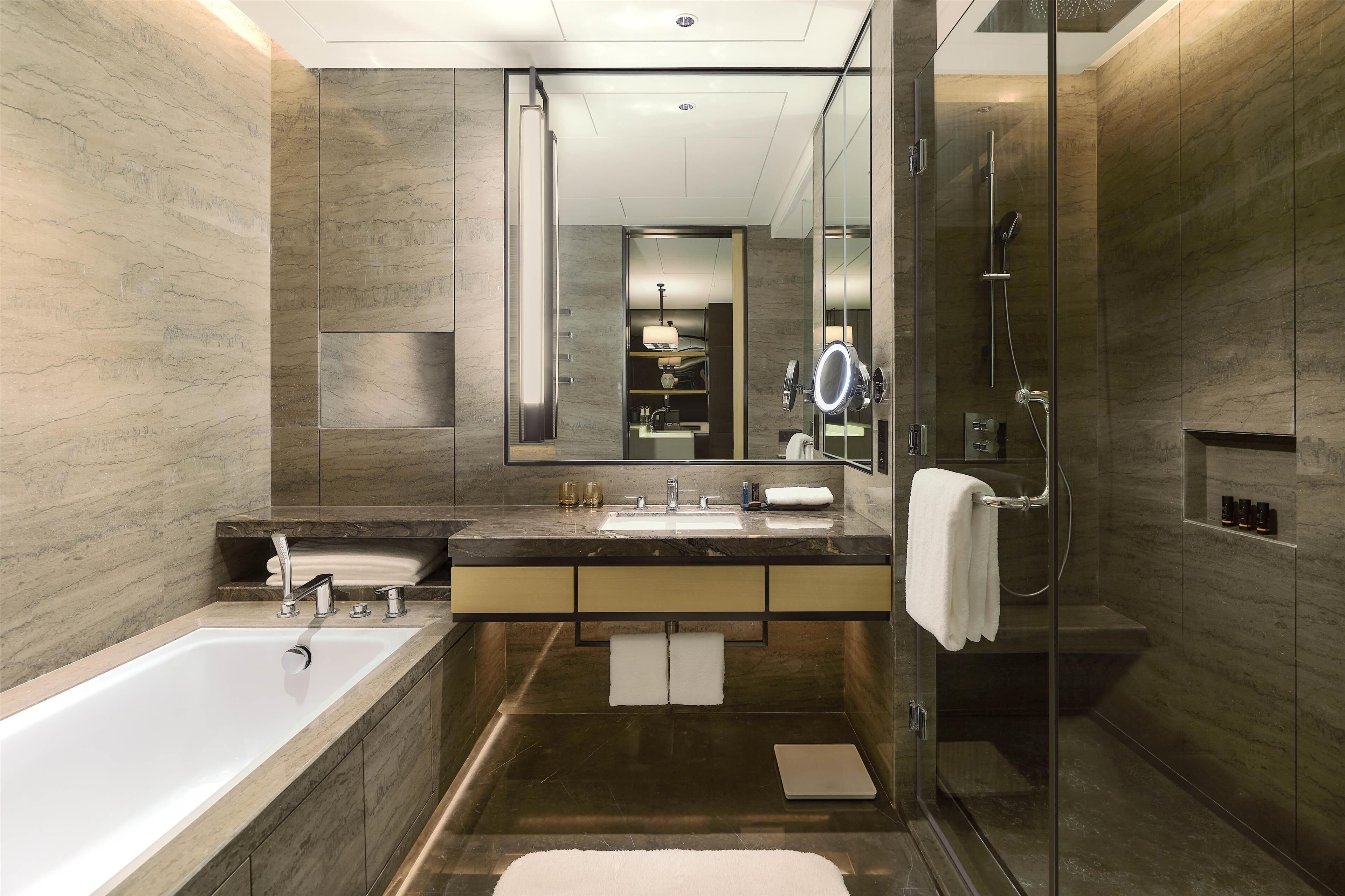 Un baño moderno con un espejo grande, una bañera, una ducha y un tocador con lavabo y encimera.