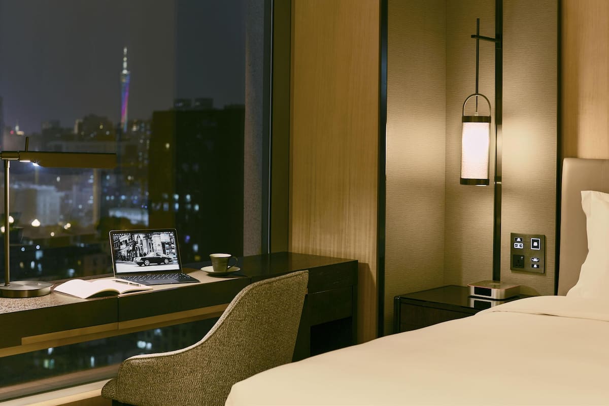 Quarto de hotel com escrivaninha, laptop e vista para a cidade.