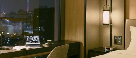 Ein Hotelzimmer mit Schreibtisch, Laptop und Blick auf die Stadt.