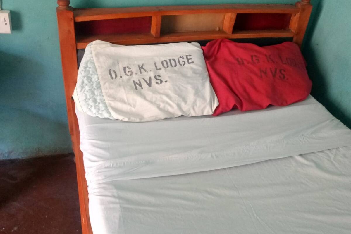 A bed with a wooden headboard and two pillows, one white and one red, with text on them.