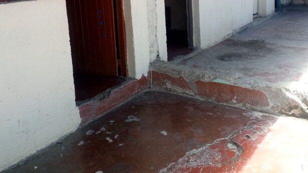 A corridor with multiple doors and windows, some open, in a building with white walls and a concrete floor. - Dgk Lodge (Naivasha)