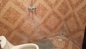 A bathroom with patterned tiles, a toilet, and a shower. - Dgk Lodge (Naivasha)