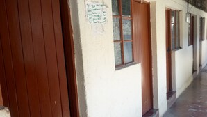 A building with a brown door and windows, a sign on the wall, and a concrete floor. - Dgk Lodge (Naivasha)