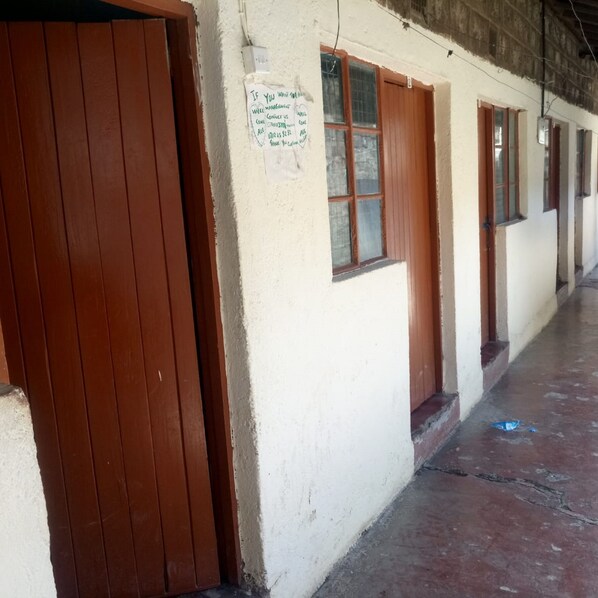 A building with a brown door and windows, a sign on the wall, and a concrete floor.