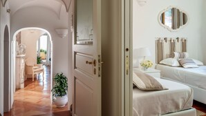 A hotel room with two beds, a large mirror, a potted plant, and a view of the hallway. - Casa Dorotea (Meta)