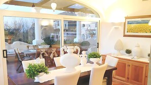 A dining area with a wooden table, white chairs, and a glass door leading to an outdoor patio. - Casa Dorotea (Meta)