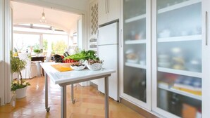 A modern kitchen with a central island, white cabinetry, and a view into the dining area. - Casa Dorotea (Meta)