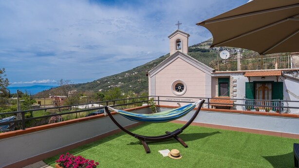 Una hamaca en una terraza en la azotea, con vistas a una iglesia y colinas.