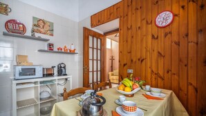Un comedor con una mesa lista para dos, una tetera y un frutero.