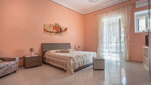Un dormitorio con cama, mesitas de noche, una silla y una pequeña mesa.